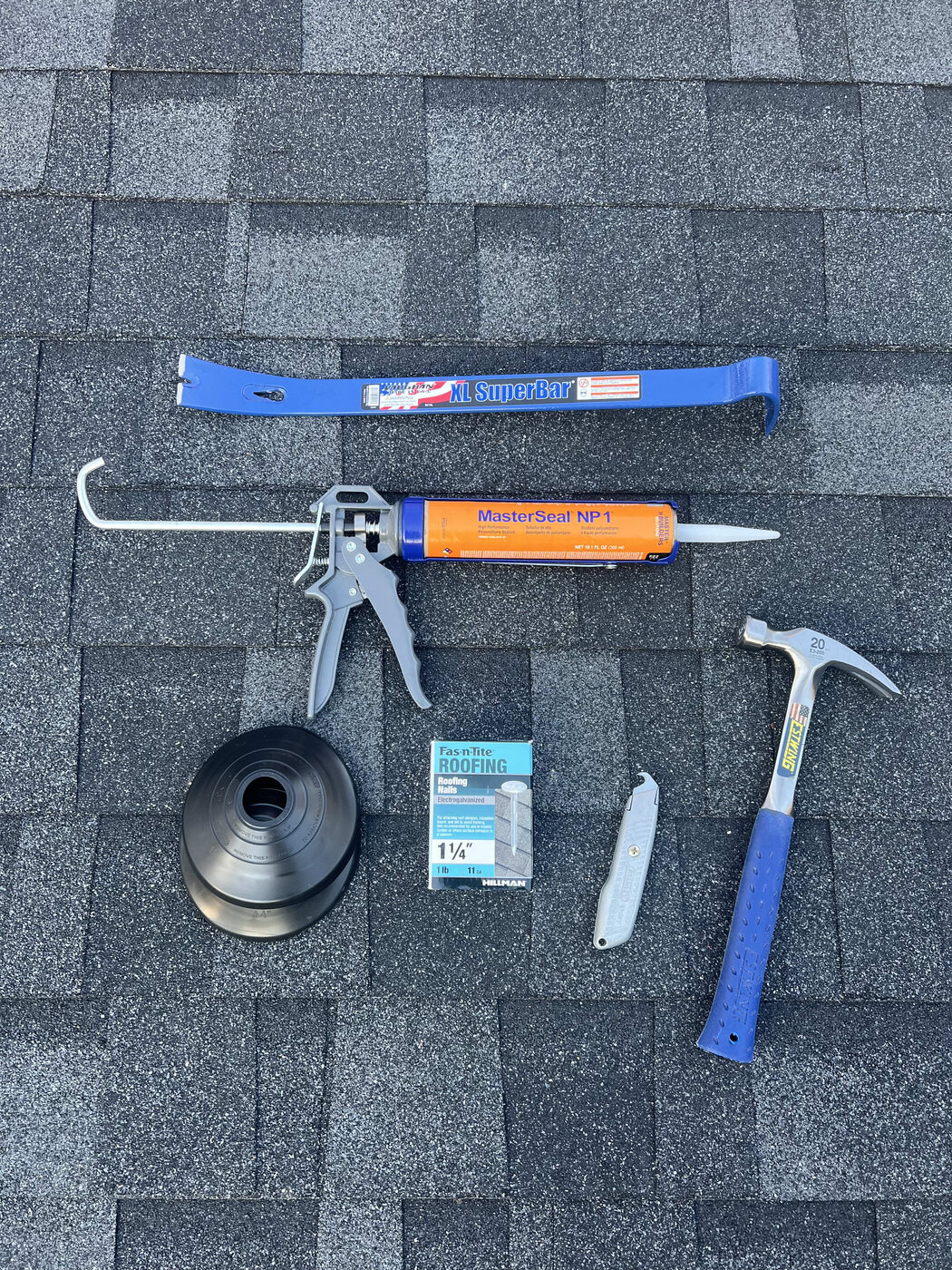 Sealant, hammer and roofing tools on new shingles